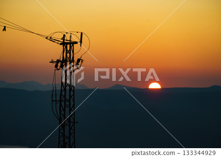 High voltage towers on coast at sunset High voltage towers on coast at sunset 133344929