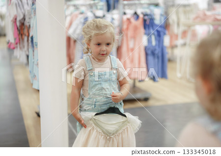 little girl choosing baby clothes in shop 133345018