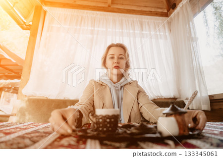 Woman with Blonde Hair in a Beige Coat, Enjoying a Cup of Coffee in a Cozy Cafe Woman with Blonde Hair in a Beige Coat, Enjoying a Cup of Coffee in a Cozy Cafe 133345061
