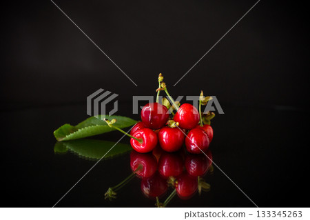 a handful of ripe red cherries on a black background 133345263
