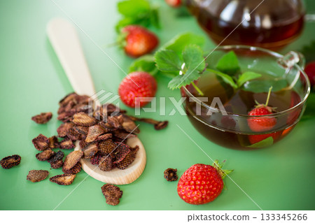 Bright strawberry tea in transparent glassware on a green background 133345266