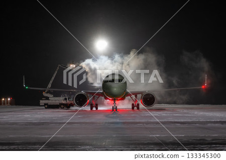 Ground deicing of a passenger jetliner on the night airport at winter 133345300