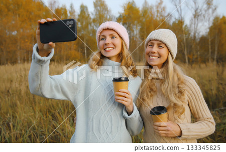Modern happy women friends taking selfie with phone in park, girlfriends having fun together 133345825