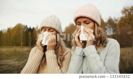 Sick women sneezing blow nose using tissue, unhealthy suffering girls feels unwell outdoors Sick women sneezing blow nose using tissue, unhealthy suffering girls feels unwell outdoors 133345832