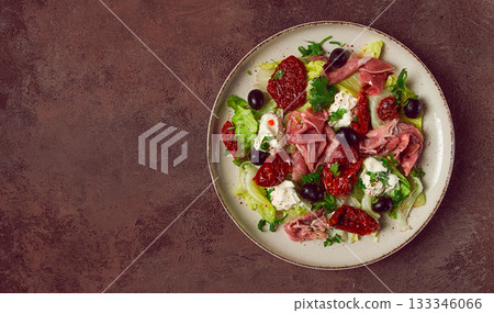 salad with dried tomatoes, prosciutto, soft cheese, olives, homemade, top view, 133346066