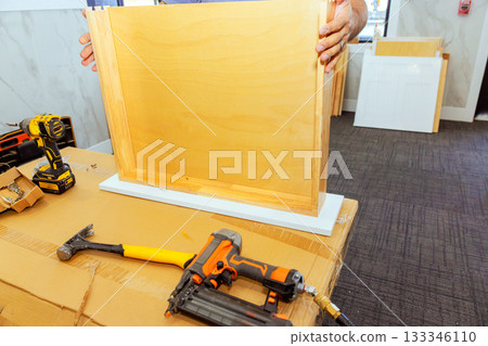 Wood worker is working on assembling wooden drawer frame while using tools at workspace Wood worker is working on assembling wooden drawer frame while using tools at workspace 133346110
