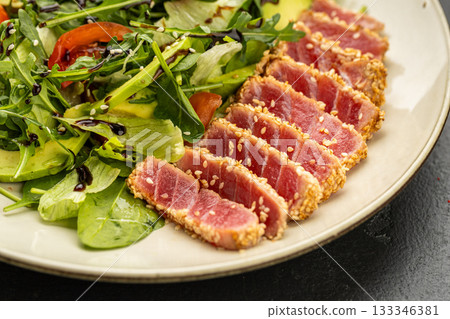 Seared tuna salad with avocado, arugula and sesame on plate, healthy gourmet lunch 133346381