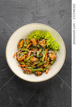 Mussel and green bean salad with sesame in a ceramic bowl on dark stone Mussel and green bean salad with sesame in a ceramic bowl on dark stone 133346382