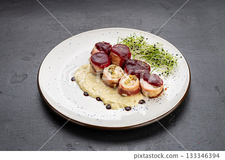 Chicken bacon roulade with berry sauce and creamy puree, plated with microgreens 133346394