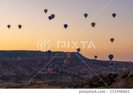 Hot air balloon flying over rocky landscape at sunrise in Cappadocia. Turkey Hot air balloon flying over rocky landscape at sunrise in Cappadocia. Turkey 133346661