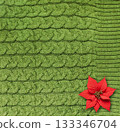 Christmas background with poinsettia on wool sweater texture of green color with cable knitting stitch pattern. Winter holiday backdrop with Christmas Star flower. Copy space for text 133346704