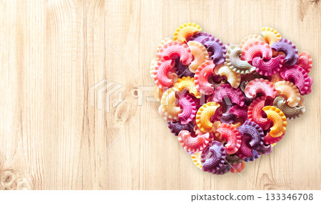 Horizontal banner with Heart formed from uncooked multi-colored pasta on wood texture. Italian food, cuisine, dietary choices, food and love concept. Dried pasta in heart shape. Copy space for text Horizontal banner with Heart formed from uncooked multi-colored pasta on wood texture. Italian food, cuisine, dietary choices, food and love concept. Dried pasta in heart shape. Copy space for text 133346708
