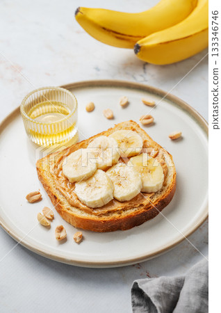 Peanut butter sandwich and banana on a plate on a marble background 133346746
