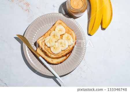 Peanut butter sandwich and banana on a plate on a marble background 133346748