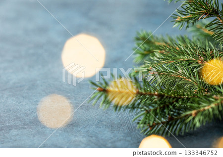 Fir branches and Christmas lights with a bokeh effect on a dark blue background 133346752