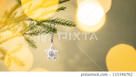 Fir tree branches with a Christmas tree ornament with a bokeh effect from the garland 133346762