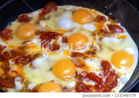 Fried eggs with tomatoes in pan 133346779