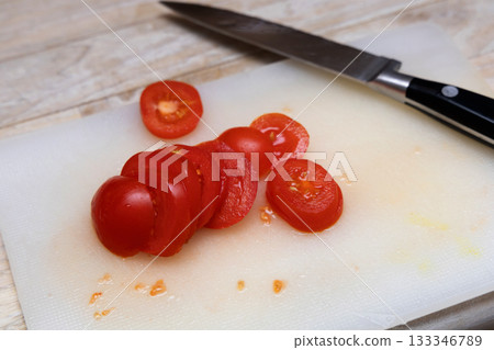 Small tomato chopped on synthetic cutting surface. 133346789