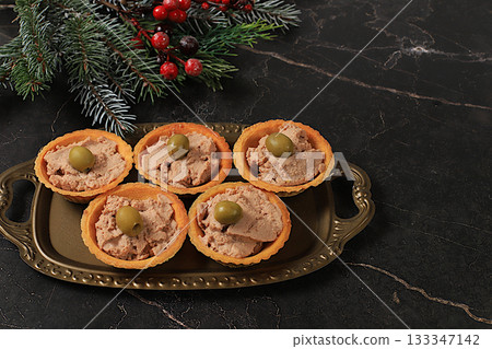 A tray of tartlets with pate, cheese, and olives on a concrete table,a Christmas Eve concept. Christmas and New Year's dishes, a selection of appetizers and treats for the festive table. A tray of tartlets with pate, cheese, and olives on a concrete table,a Christmas Eve concept. Christmas and New Year's dishes, a selection of appetizers and treats for the festive table. 133347142