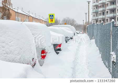 Poland, Krakow, 12.03.2023, snowfall, snowy street with cars after a blizzard 133347260