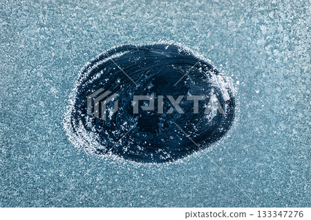 Frosted Window With a Clear Patch Revealing an Icy Blue Background During a Cold Winter Morning Frosted Window With a Clear Patch Revealing an Icy Blue Background During a Cold Winter Morning 133347276