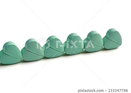 Turquoise heart-shaped cardiology pills lined up on a white background. Turquoise heart-shaped cardiology pills lined up on a white background. 133347786