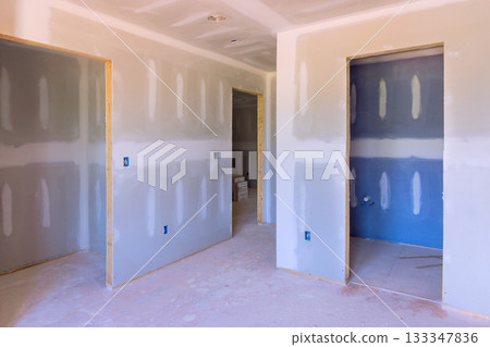 Unfinished interior features drywall, new door openings, clean construction site in residential building. 133347836