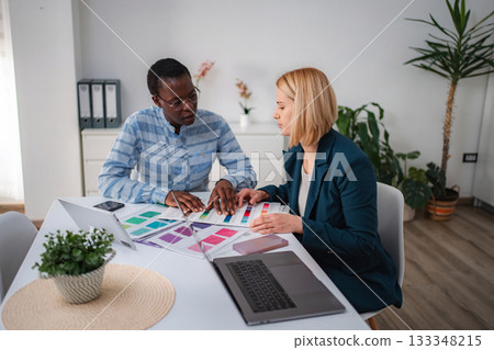 Diverse colleagues discussing color palettes for creative design project 133348215