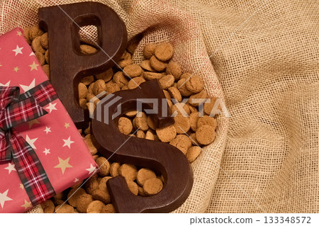 Festive Sinterklaas Treat. Chocolate letters and cookies on burlap with a wrapped gift 133348572