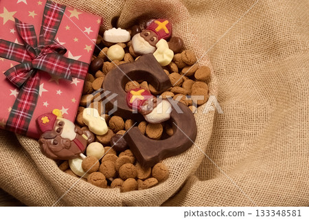 Festive Sinterklaas Display. A burlap basket with chocolate letters, Sinterklaas figures, and a starry gift box 133348581
