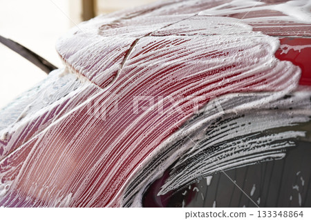 White soap and foam strokes on red plates of car washed in self serve carwash, closeup detail White soap and foam strokes on red plates of car washed in self serve carwash, closeup detail 133348864