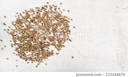 Unpeeled cannabis seeds on white stone like board, view from above - space for text right side 133348874