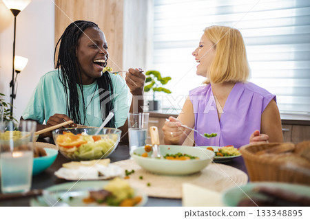 Friends enjoy a joyful meal together in a cozy dining space Friends enjoy a joyful meal together in a cozy dining space 133348895
