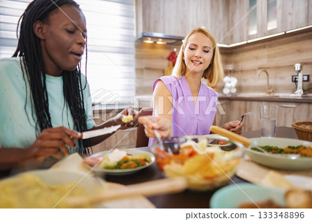 Friends enjoying a vibrant meal in a cozy kitchen setting Friends enjoying a vibrant meal in a cozy kitchen setting 133348896