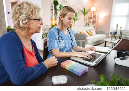 Caring interaction between a nurse and a senior woman in a cozy home setting 133348921