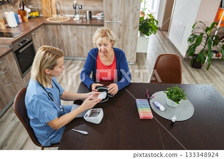 Caregiver provides support to elderly woman in cozy kitchen setting Caregiver provides support to elderly woman in cozy kitchen setting 133348924