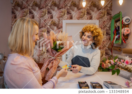 Customer enjoys personal service while purchasing flowers in a charming boutique setting 133348934