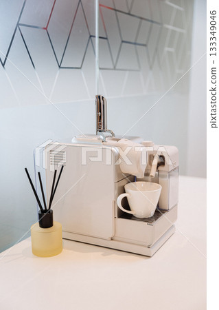 White coffee machine with cup and aroma diffuser on counter, modern office interior 133349046
