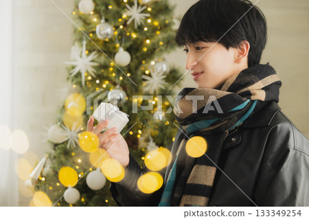 A man holding a present in front of a Christmas tree 133349254