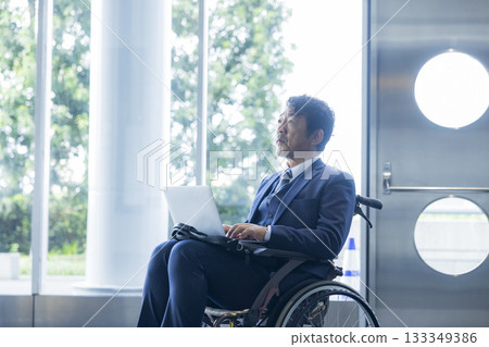 一名身穿西裝的男子坐在輪椅上 133349386