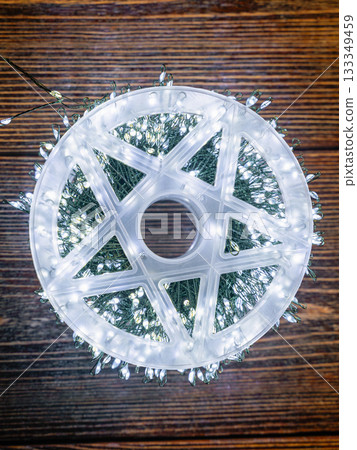 Garland glows with white light on a brown wooden background. Garland glows with white light on a brown wooden background. 133349459