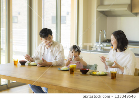 一家人其樂融融地圍坐在餐桌旁 一家人其樂融融地圍坐在餐桌旁 133349546