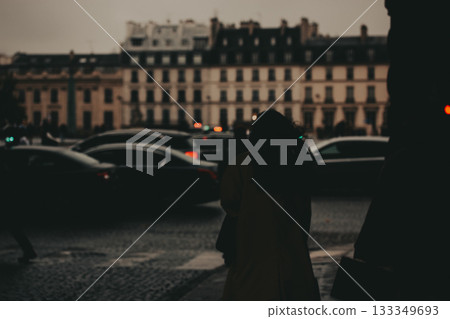 Blurred cityscape with people in silhouette. A blurry shot of a city street with people in silhouette, with buildings and lights in the background. 133349693