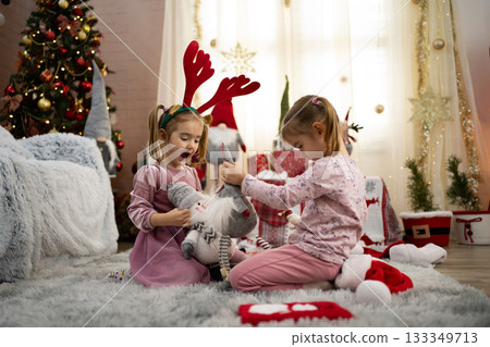 Two little girls playing with Christmas gnomes in a decorated living room 133349713
