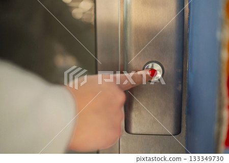 Hand pressing an elevator button in a modern building hallway Hand pressing an elevator button in a modern building hallway 133349730