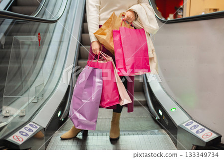 Shopping venture on an escalator with colorful bags in hand Shopping venture on an escalator with colorful bags in hand 133349734