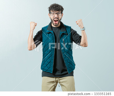 Excited young man celebrating looking at camera raising arms isolated. Happy guy with sunglass celebrating something Excited young man celebrating looking at camera raising arms isolated. Happy guy with sunglass celebrating something 133351165