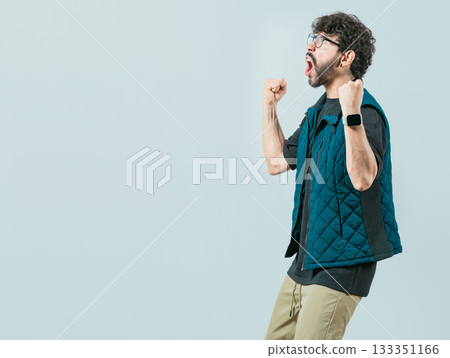 Happy guy with sunglass celebrating something. Excited young man celebrating looking at camera raising arms isolated 133351166