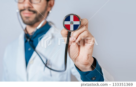 Doctor holding stethoscope with Dominican Republic flag. Dominican Republic health and care concept. Dominican Republic flag on stethoscope Doctor holding stethoscope with Dominican Republic flag. Dominican Republic health and care concept. Dominican Republic flag on stethoscope 133351369