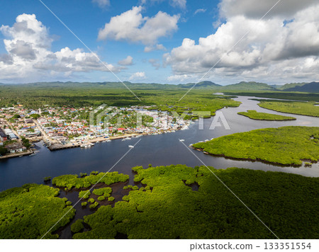Town along riverbanks surrounded by mangrove forest and mountains in background. Siargao, Philippines. 133351554